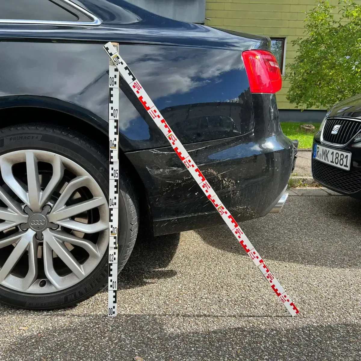 Vermessung eines Heckschadens mit Messlatte an einem schwarzen Audi in Regensburg